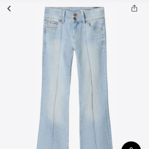 Low waist bootcut jeans - Snygga ljusblå jeans med bootcut-modell och markerade pressveck framtill. Jeansen har dubbla knappar i midjan, klassiska fem fickor och är tillverkade i mjukt denimtyg. Perfekta för en trendig och avslappnad look.