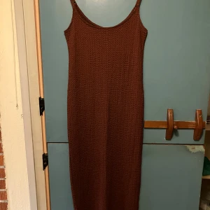 Röd/Brun långklänning från H&M - Säljer en röd/ brun långklänning från H&M med smala axelband och stretchigt, strukturerat tyg. Klänningen har en enkel, rak passform och är perfekt för dig som gillar minimalistisk stil. Superskön och lätt att styla med sneakers eller sandaler.