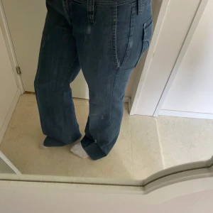 Blå jeansbyxor från J.Lindeberg - Säljer ett par klassiska blå jeans från J.Lindeberg med bootcut och snygga detaljer på bakfickan. Byxorna har normal passform. Jeansmaterialet är slitstarkt och bekvämt.