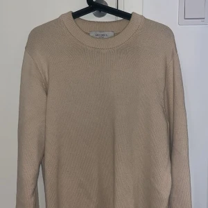 Beige stickad tröja från Les Deux - Säljer en stilren beige stickad tröja från Les Deux. Tröjan har rund halsringning och långa ärmar, perfekt för lager-på-lager eller som den är. Enkel och klassisk design som passar till mycket. Ordinariepris är 999kr