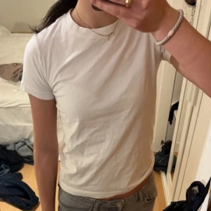 Vit basic t-shirt - En klassisk vit t-shirt med rund hals och korta ärmar. Modellen är enkel och passar perfekt till jeans eller shorts. 