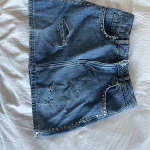 Jeanskjol med nitar - Säljer en jätte fin jeans skol med nitar längst sidorna har köpt den secondhand så tyvärr har den ej någon pris lapp storlek 34 