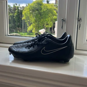 Svarta Nike fotbollsskor med snörning - Jag säljer mina gamla svarta fotbollsskor från Nike är bara använda i en säsong det är inget fel på dem!