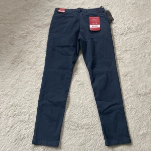 Mörkblå chinos från Replay - Snygga mörkblå chinos från Replay med klassisk passform. Byxorna har normal midja, raka ben och stängs med dragkedja och knapp. Perfekta för en stilren och enkel look. 