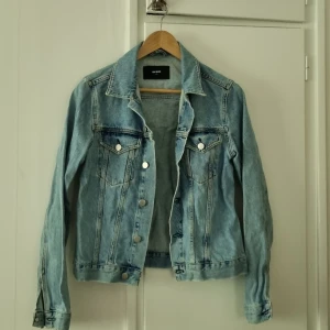 Ljusblå jeansjacka från Monki - Säljer en klassisk ljusblå jeansjacka från Monki med silverfärgade knappar och två bröstfickor. 