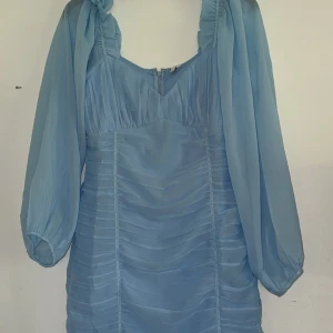 Ljusblå kortklänning med puffärmar - Supersöt ljusblå klänning med transparenta puffärmar och rynkade detaljer framtill. Materialet känns lätt och luftigt. Endast testad, tyvärr för liten för mig. Inget fast pris allt går att diskutera 🥰