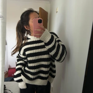 Randig stickad tröja i svart och vitt - Säljer en mysig stickad tröja med breda svarta och vita ränder. Tröjan har lång ärm, ribbade muddar och en avslappnad passform.