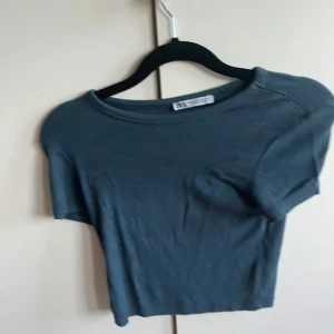 Mörkblå croppad t-shirt från Zara - En enkel och stilren mörkblå croppad t-shirt från Zara. T-shirten har rund halsringning och korta ärmar, perfekt för en avslappnad look. Tillverkad i mjukt bomullsmaterial.