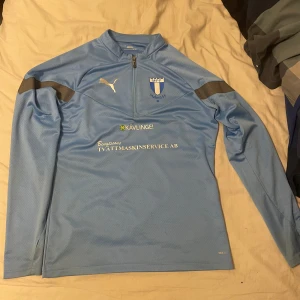 Långärmad fotbollströja från Malmö FF - Ljusblå långärmad fotbollströja från Malmö FF.. Tröjan har halv dragkedja. Perfekt för träning, match eller bara nu till sommaren.