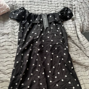 Svart offshoulder klänning med blommigt mönster från Motel - Helt oanvänd off shoulder klänning med volang upptill. Säljer eftersom den är för liten, prislapp finns kvar. Skriv privat för bättre bilder💖
