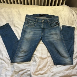 Replay Anbass ljusblå jeans - Säljer ett par Replay Anbass jeans i ljusblå tvätt med klassisk femficksdesign och snygga slitningar. Jeansen har normal, med Replay-logga på bakfickan och läderpatch i midjan.