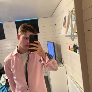 Ljusrosa skjorta från Dressmann - Säljer en ljusrosa skjorta från Dressmann i storlek M. Skjortan har klassisk krage, knäppning framtill och är tillverkad i en bomullsblandning. Perfekt för dig som vill ha en stilren och enkel look.