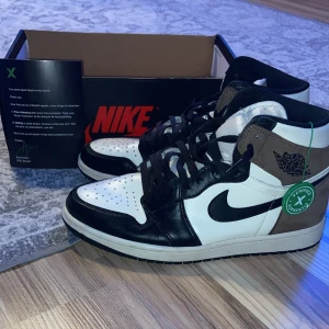Nike Air Jordans 1 - Snygga Nike Air Jordans i en stilren kombination av svart, vitt och brunt. Skorna har klassisk snörning och en rund tå. Perfekta för dig som vill ha en ikonisk sneaker med en modern touch. Vita skosnören ingår också. Hör av er vid intresse och fler bilder!