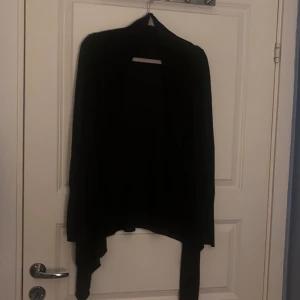 Svart kofta - Säljer en stilren svart kofta med lång ärm. Perfekt för kyligare dagar och enkel att matcha med olika outfits. Koftan har en öppen design utan knappar. Passar storlek Small/Medium