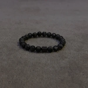 Grått svart pärlarmband - Elegant svart pärlarmband med runda pärlor och en central fyrkantig detalj. Perfekt för att ge en stilren touch till din outfit.