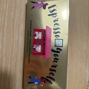 Espresso Yourself ögonskuggspalett - Ögonskuggspalett från The Beauty Crop med temat 'Espresso Yourself'. Förpackningen har en guldig design med illustrationer av personer och en café-skylt. Innehåller ögonskuggor med kaffeextrakt.