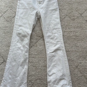 Vita bootcut jeans - Snygga vita bootcut jeans med hög midja men  man kan vika ner för mid rise och knappstängning. Perfekta för en stilren look. De har en klassisk design med fem fickor och är tillverkade i ett bekvämt material. De har fyra knappar. Storlek är 11-12 år. Fläcken på jeansen  kommer tvättas bort och ej synas❣️