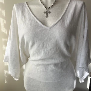 Vit tröja med v-ringning - Vit tröja som sitter supersnyggt på midjan, med djup v-ringning, vida ärmar trekvartsärmar och lös passform. Står ingen storlek, men uppskattar till M🩷 
