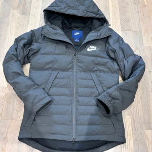 Grå Nike jacka - Säljer en stilren svart dunjacka från Nike med huva och dragkedja. Perfekt för detta väder. Pris kan diskuteras vid snabb affär!