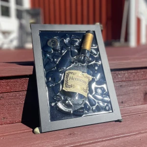 Hennessy Cognac Tavla - Unikt konstverk med en krossad Hennessy-flaska inramad i svart. Flaskan är omgiven av krossade glasbitar och handgjord av Epoxycreations🤩