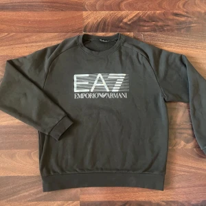 Oliv grön sweatshirt från Emporio Armani - Snygg svart sweatshirt från Emporio Armani med EA7-logga på bröstet. Storleken är S men passar mer som XS/S