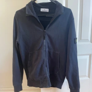 Blå Stone island full zip crewneck - Full zip från Stone island som är riktigt snygg. Skicket är bra för mer information kom privat. Köpte den på johnells för ett tag sen för 3300 eller nåt liknande!. Storleken är M men passar S också. PRISET GÅR O DISKUTERA VID SNABB AFFÄR