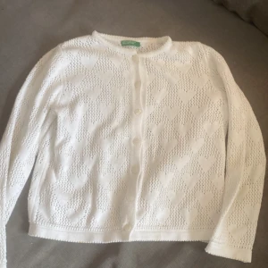 Vit kofta från United Colors of Benetton - Säljer en söt vit kofta från United Colors of Benetton med hjärtmönster. Koftan har långa ärmar och knappar framtill. Perfekt nu inför våren/sommaren!❤️🌺Vet tyvärr inte storleken men skulle gissa runt xxs ungefär, beroende på hur man vill att den ska sitta!