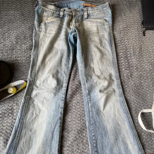 Lågmidjade Jeans - Säljer ett par snygga blå bootcut jeans från Diesel. De har en klassisk femficksdesign och en lätt slitning för en cool look. Perfekta för en avslappnad stil.