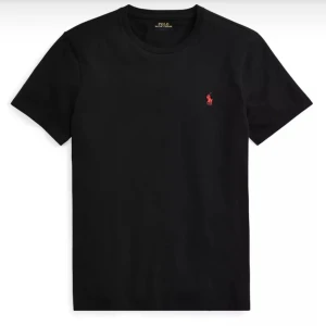 Svart t-shirt från Ralph Lauren - Säljer en klassisk svart t-shirt från Ralph Lauren med det ikoniska röda logotypbroderiet på bröstet. T-shirten har en normal passform och är tillverkad i mjuk bomull. Perfekt för en stilren look.