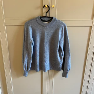Blå stickad tröja - Säljer en jättemysig blå stickad tröja från only med rund hals och långa ärmar. Materialet är mjukt och sticks inte alls! Lite tecken på användning på ärmarna då de är något uttöjda men annars fint skick!
