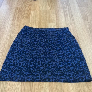 Blå leopardmönstrad kjol - Snygg blå kjol med leopardmönster. Perfekt för att ge din outfit en cool touch. Kjolen har en normal passform och är i en kort modell. Knappt andvänd