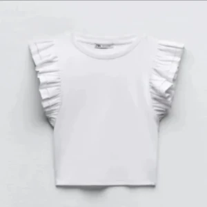 Vit ribbad topp med volangärmar - Säljer en söt vit ribbad topp från Zara med volangdetaljer på ärmarna.  Använd fåtal gånger och har inga defekter. 