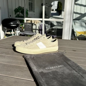 Beige sneakers från Tom Ford - Snygga beige sneakers från Tom Ford med vit detalj på sidan. Skorna har en klassisk rund tå och snörning framtill. Perfekta för en stilren look. Nypris: 5700kr. Mitt pris 3000