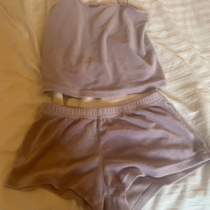 Ljuslila oneshoulder topp - Säljer en ljuslila oneshoulder topp i mjukt material. Perfekt för en avslappnad stil eller som en del av en mysig hemmalook. Toppen har en enkel och stilren design kommer även med shorts.