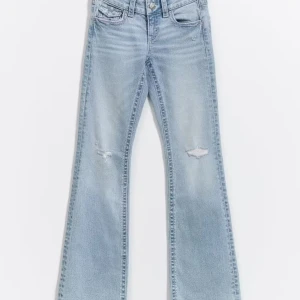 Ljusblå bootcut jeans med slitningar - Säljer ett par ljusblå bootcut jeans med slitningar vid knäna från gina. Storlek 164