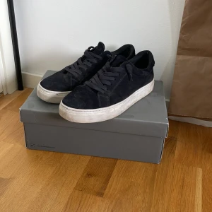 Mörkblå mocka från vagabond (Paul 2.0) - Säljer ett par svarta sneakers med platt vit sula och rund tå. Skorna har snörning och är tillverkade i mocka, vilket ger en stilren och enkel look. Perfekta för dig som gillar klassiska och bekväma skor.