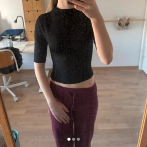 Svart  topp med lite högre krage  - Säljer en svart, croppad topp med halvpolo och halvlånga ärmar. Toppen är tight och tillverkad i ett stretchigt material som sitter snyggt på kroppen. Perfekt att styla med både jeans och kjol. Helt oanvänd 