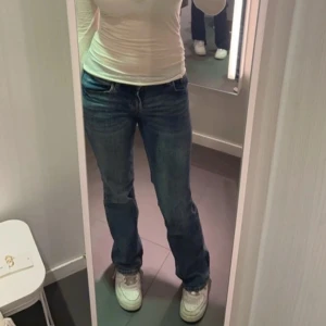 Lågmidjade jeans - Säljer ett par klassiska blå jeans med rak passform och normal midja. Jeansen har fem fickor och stängs med dragkedja och knapp. Perfekta till sneakers och en enkel topp.