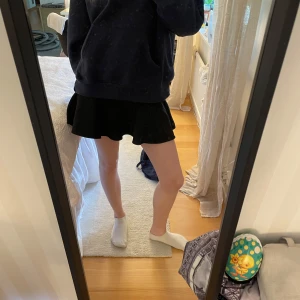 Svart kortkjol från Zara - Säljer en svart kortkjol från Zara med utsvängd form. Kjolen har en enkel och stilren design utan synliga detaljer och passar perfekt till många olika looks. Materialet känns mjukt och följsamt.