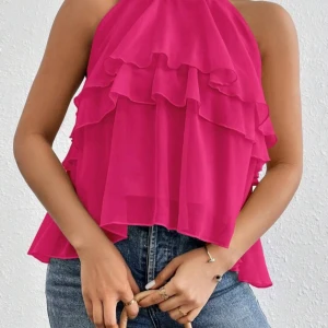Rosa volangtopp med halterneck - Säljer en snygg rosa topp med halterneck och flera lager volanger. Toppen är ärmlös och har en luftig passform, perfekt för varma dagar. Styla med jeans eller kjol för en trendig look! Jag har aldrig använt den vara provat!