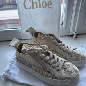 Chloé sneakers  - Exklusiva sneakers från Chloé i modellen Lauren, med vacker spetsdesign och den ikoniska vågiga sulkanten. Skorna är i ljusbeige/ivory färg med ton-i-ton Chloé-logga i spetsen, vilket ger en feminin och lyxig känsla. Bekväma, stilrena och perfekta både till vardags och lite finare tillfällen.  Skick: Väldigt fint skick, endast sparsamt använda.                                                                                   Nypris ca 6500kr  Pris: 4000kr  Ingår: Original dustbags från Chloé. 