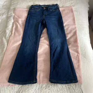 Blå flare jeans med hög midja från H&M - Snygga blå jeans med flare-ben och hög midja från H&M. Klassisk femficksmodell med knapp och dragkedja framtill. Perfekta för dig som gillar en retroinspirerad look med utsvängda ben. Jag tvättar produkten innnan jag skickar den. Det går att pruta om ni vill 😊