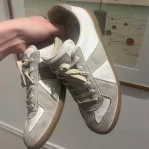 Vita och grå sneakers med mockadetaljer - Säljer ett par maison margiela i perfekt skick! stilren och avslappnad look. Storlek 41/1,2 : pris 2999kr 
