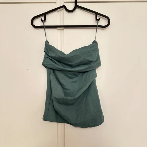 Grön draperad off shoulder topp - Snygg grön off shoulder topp och draperad framsida. Perfekt för varma dagar eller när du vill ha en stilren look. Toppens material känns mjukt och lätt mot huden.