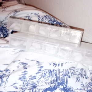 Vita nageltippar i förvaringsbox (2lådor) - Säljer ett set med vita nageltippar  i olika storlekar, sorterade i en genomskinlig plastbox med flera fack. Perfekt för att skapa snygga naglar hemma. Naglarna är odekorerade och har en naturlig form. 60kr för en låda annars 120kr för båda!