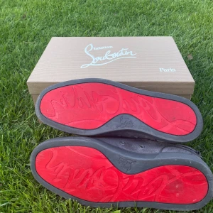 Gråa sneakers från Christian Louboutin - Säljer ett par gråa sneakers från Christian Louboutin med klassisk röd sula. Skorna är i mocka och har snörning samt rund tå. Kommer med originalkartong, dustbag och äkthetskort.