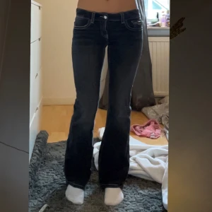 Svarta bootcut jeans med vita sömmar - Säljer ett par svarta bootcut jeans med vita kontrastsömmar och klassiska fickor både fram och bak. Jeansen har låg midja och stängs med knapp och dragkedja. Perfekta för dig som gillar en retro vibe!  Från Gina tricot i storlek 158 men passar mig som är 163