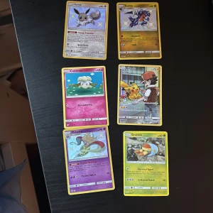 Pokémonkort - blandad samling - Säljer sex Pokémonkort: Eevee, Gabite, Cottonee, Pikachu, Malamar och Grubbin. Korten har olika färger och motiv, vissa med holografisk effekt. Perfekt för samlare eller Pokémonfans som vill utöka sin samling.
