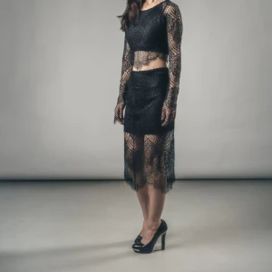 Svart långkjol i spets/For Love & Lemons - Säljer en svart långkjol i genombruten spets med snyggt mönster. Kjolen har en tight underkjol och ett transparent lager ovanpå som ger en cool och elegant look. Perfekt för dig som vill sticka ut med en unik och trendig stil. Märket är For Love & Lemons 