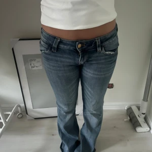 Blå bootcut jeans från Levis - Snygga blå jeans från Levis med bootcut passform och låg midja. Klassisk femficksmodell med slitningar och ljus tvätt. Perfekta för dig som gillar en avslappnad men ändå trendig look.